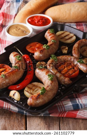 sausage with grilled vegetables and buns with sauce on the table. vertical