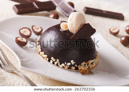Delicious chocolate cake with nuts, topped with macaroon on a plate close-up. horizontal