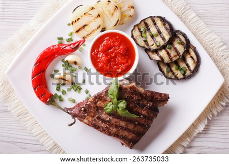 appetizing beef steak, grilled vegetables and sauce on a plate. horizontal view from above