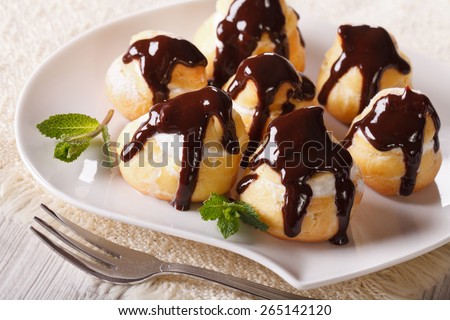 Delicious profiteroles with cream and chocolate glaze on a plate. horizontal
