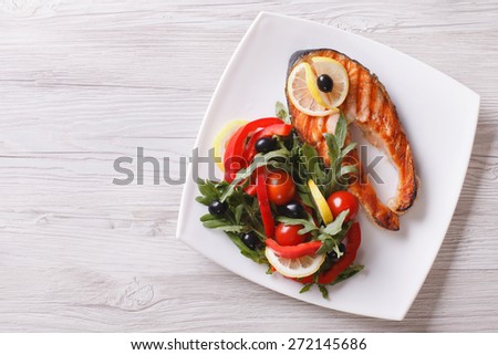 Grilled red fish salmon and a salad on a plate. horizontal view from above