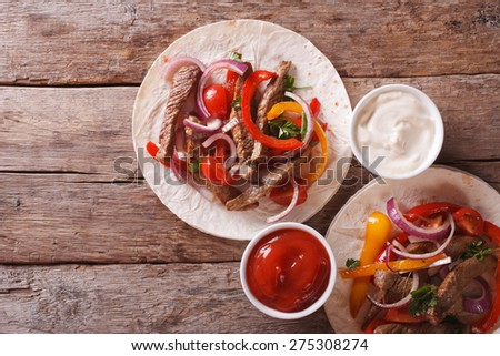 tortillas with meat, vegetables and sauce on the table. horizontal view from above