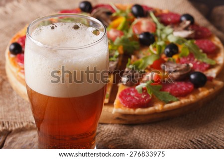 beer with foam close-up on background pizza on the table. horizontal