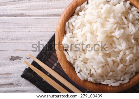 Japanese food: steamed rice in a wooden bowl and chopsticks close-up. horizontal view from above