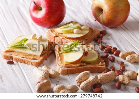 sandwiches with peanut butter and an apple on the table. horizontal