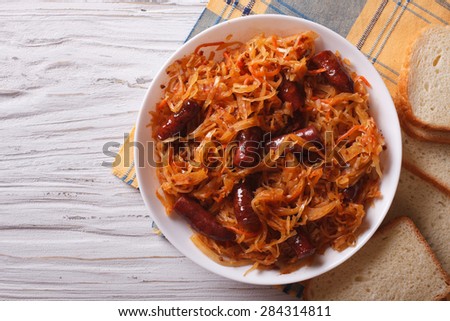 stewed cabbage with sausages in white plate. horizontal view from above