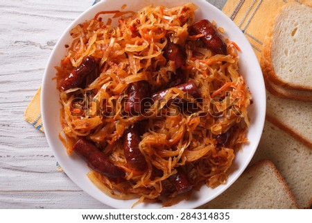 stewed cabbage with sausages close-up in white plate. horizontal view from above