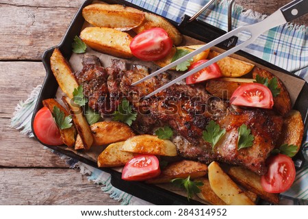 homemade barbecue: meat and potatoes close up on a grill pan. horizontal view above, rustic style