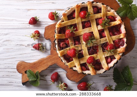 delicious strawberry pie in the baking dish on the table. vertical view above, rustic style