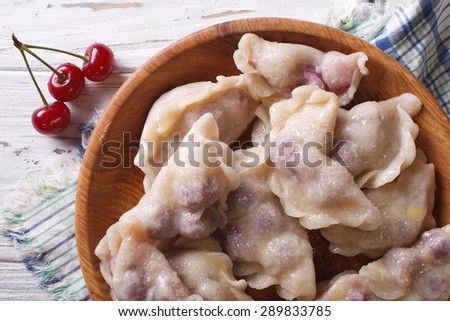 sweet dumplings with cherries in a wooden bowl.  horizontal top view