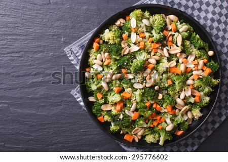 Healthy food: Broccoli salad with peanuts and carrots close-up on a black plate. horizontal view from above