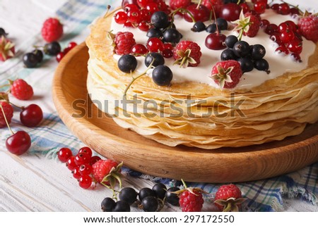 Stack crepes with berries and cream close-up on a plate. horizontal