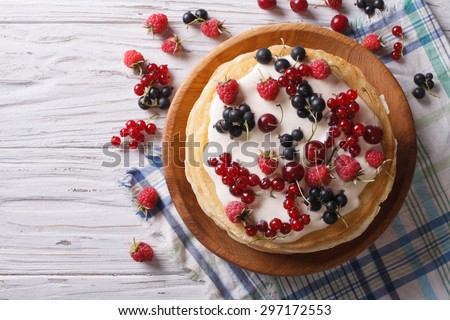 homemade stack of crepes with berries and cream close-up on the table. horizontal view from above