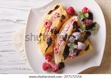 raspberry crepes with chocolate and mint close-up on a plate. horizontal view from above