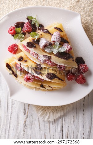 raspberry crepes with chocolate and mint close-up on a plate. Vertical view from above