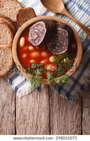 Delicious soup with black pudding Fabada asturiana in a wooden bowl. vertical top view