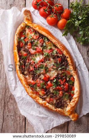 Turkish pide pizza with meat and vegetables close-up on the table. vertical top view