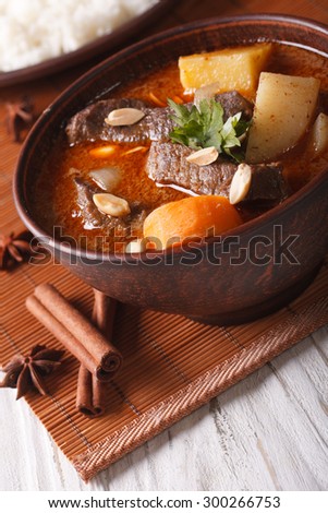 Traditional Thai beef massaman curry with peanuts close-up in a bowl. vertical