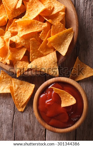 Nachos corn chips with spicy sauce on the table. vertical view from above closeup