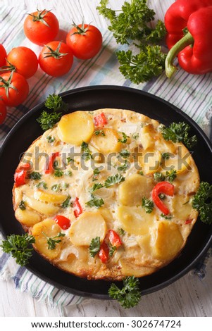 Spanish tortilla with potatoes and vegetables close-up in a pan. vertical top view