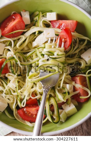 Dietary food: zucchini pasta with feta and tomatoes on a plate close-up. vertical view from above