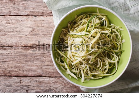 Useful raw zucchini pasta in a bowl close up on the table. horizontal top view