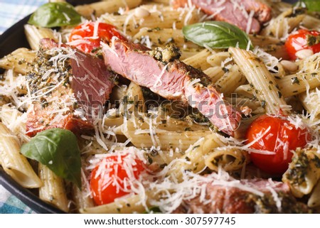 penne pasta with meat, tomato and pesto close up on a plate. Horizontal