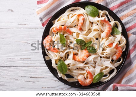 fettuccini pasta in cream sauce with shrimp on a plate on the table. horizontal view from above