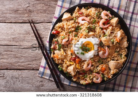 Asian fried rice nasi goreng with chicken, prawns, egg and vegetables horizontal view from above