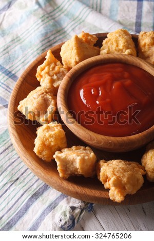 Fast food: crispy popcorn chicken fillet with sauce close-up on a plate. Vertical