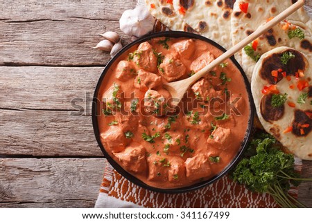 Indian tikka masala chicken and naan flat bread on the table. horizontal top view