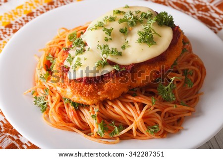 Italian food: Chicken Parmigiana and spaghetti close up on a plate on the table. horizontal