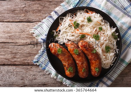 grilled sausages and sauerkraut on a plate on a table close-up. horizontal top view