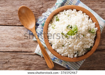 Cauliflower rice with basil close up in a bowl on the table. horizontal top view