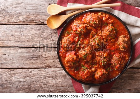 Meatballs with spicy tomato sauce on a plate on the table. horizontal view from above