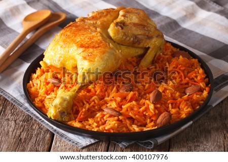 Traditional Arabic food: kabsa with chicken and almonds close-up on a plate. Horizontal