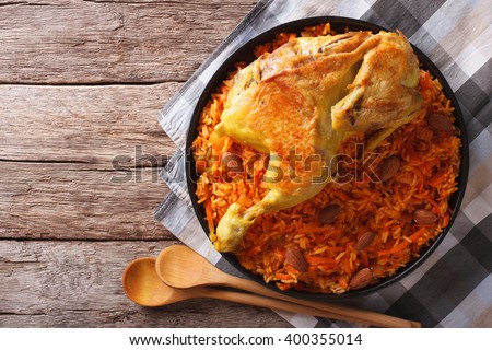 Kabsa of chicken with rice and vegetables on a plate on the table. horizontal view from above