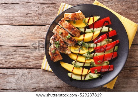 roast chicken with fresh mango, avocado and peppers with balsamic sauce close-up on a plate. Horizontal view from above