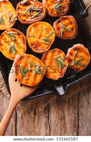 Healthy food: Grilled sweet potatoes with rosemary on the grill pan on the table close-up. vertical view from above