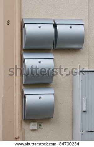 A lot of metal mailboxes on the wall of an apartment house