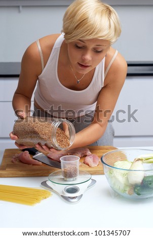 Portrait of pretty blond girl in the kitchen making pasta