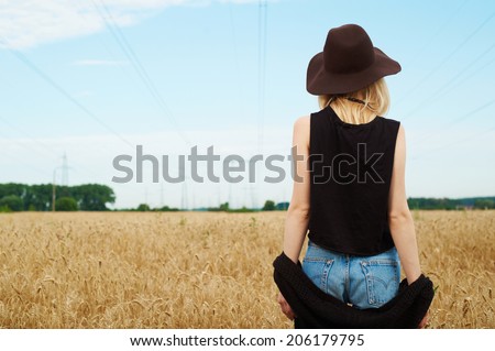 blond girl in the fields wearing brown hat. sun lit portrait