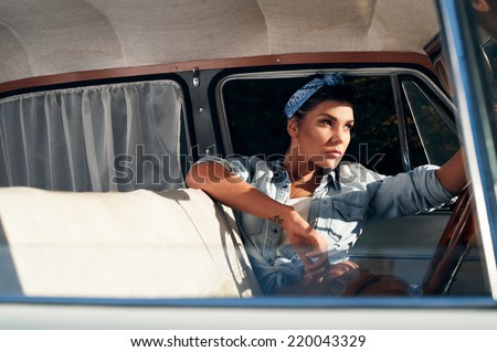 pin-up lady with tattoos wearing shirt in retro car