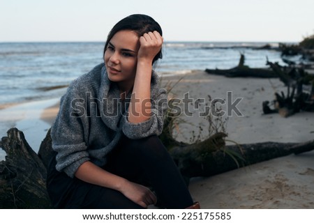 brunette on sea coast in autumn wearing grey pullover