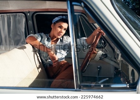 pin-up lady with tattoos wearing shirt in retro car