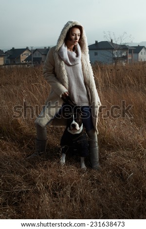 woman standing with staffordshire terrier in fields behind country town