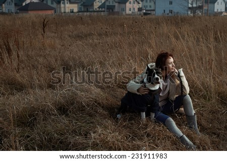 woman sitting with staffordshire terrier in fields behind country town