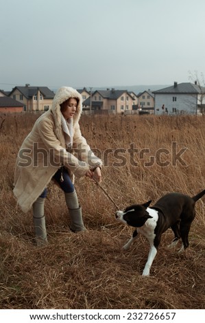 woman playing with staffordshire terrier in fields behind country town