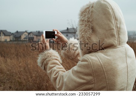 woman takes photos of country town view in fields
