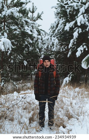 man in the winter forest on the walk with old backpack